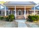 Inviting brick home with a classic front porch, white columns, and well-manicured landscaping at 10812 Dorchester Rd, Summerville, SC 29485