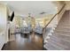 An open-concept living room features hardwood floors, a staircase, and modern decor that connects to the kitchen at 1251 Weather Helm Dr, Mount Pleasant, SC 29466