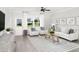 Bright living room features hardwood floors, white sofas, and a large window overlooking the backyard at 135 Royal Cainhoy Way, Huger, SC 29450