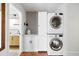 Efficient laundry room features a stacked washer and dryer, patterned wallpaper, and built-in storage, perfect for organization at 1423 Bexley St, North Charleston, SC 29405