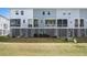 A rear view of multi-level townhomes showing the concrete base and lawn at 162 Winding River Dr, Johns Island, SC 29455