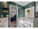 Charming bathroom featuring a soaking tub, green walls, mosaic tile backsplash, decor shelves and an open doorway at 176 Daniels Creek Cir, Goose Creek, SC 29445