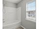 Bright bathroom featuring a shower-tub combo with white tiling, complemented by a window for natural light at 206 Woodbrook Way, Moncks Corner, SC 29461
