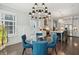 Elegant dining room with a glass table, blue upholstered chairs, and a modern chandelier at 384 Blowing Fresh Dr, Charleston, SC 29492