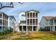 Charming rear exterior of a two-story coastal home with screened porches and a lovely landscaped yard at 384 Blowing Fresh Dr, Charleston, SC 29492