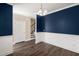 Open dining room adjacent to the foyer, featuring navy accent wall, modern light fixture and hardwood floors at 407 Stoneleigh Ln, Moncks Corner, SC 29461