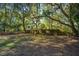 Backyard with mature trees, fenced perimeter and glimpses of the house beyond at 562 Fort Johnson Rd, Charleston, SC 29412