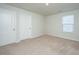 Neutral carpeted bedroom with two white doors, white walls and a window for natural light at 607 Silver Spruce St, Summerville, SC 29486