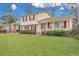 View of a home with a well-maintained lawn, red shutters, a portico, and inviting front porch at 7659 Allwood Ave, North Charleston, SC 29418