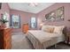 A light filled bedroom with a comfortable bed, warm lighting, and calm mauve color scheme at 8506 Kennestone Ln, North Charleston, SC 29420