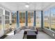 Bright sunroom with white framed windows, neutral sectional sofa, and blue accent curtains at 8506 Kennestone Ln, North Charleston, SC 29420