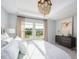 Bright main bedroom features tray ceilings, a chandelier, and windows with a view of the backyard at 1058 Tea Time Dr, Summerville, SC 29485