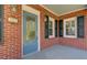 A closer view of the front porch with its painted front door, brickwork, and sconce lighting, and house number at 107 Minus St, Saint George, SC 29477