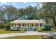 Charming single-story home with a welcoming front porch, landscaped yard, and mature trees at 1515 Devons St, Charleston, SC 29412