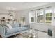 Bright living room featuring a comfortable light blue sofa and large windows overlooking a lush landscape at 1827 Nola Run, Summerville, SC 29485
