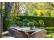 Outdoor patio with dining table and chairs, surrounded by manicured hedges and mature trees at 184 Tradd St, Charleston, SC 29401