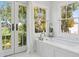 Bright bathroom featuring a soaking tub with marble surround and a gorgeous view of the property's lush landscape at 184 Tradd St, Charleston, SC 29401
