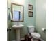 Charming powder room with pedestal sink, toilet, decorative mirror and hardwood floors at 2107 Nicholas David Path, Johns Island, SC 29455
