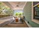 A screened-in porch is furnished with wicker furniture, a ceiling fan, and green siding at 2107 Nicholas David Path, Johns Island, SC 29455