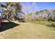 Fenced backyard with grass, treeline, and stairs leading to the home at 2641 Woodlawn Ave, North Charleston, SC 29405