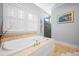 Bright bathroom with a soaking tub, plantation shutters and travertine surround at 2722 Crooked Stick Ln, Mount Pleasant, SC 29466