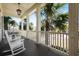 Relaxing porch with white rocking chairs and ceiling fan, perfect for enjoying the outdoors and a view of palm trees at 2722 Crooked Stick Ln, Mount Pleasant, SC 29466