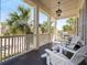 Inviting porch with white Adirondack chairs, a ceiling fan and a view of lush landscaping with palm trees at 2722 Crooked Stick Ln, Mount Pleasant, SC 29466