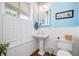 Charming powder room with blue walls, wainscoting, and a pedestal sink, enhanced by natural light at 2722 Crooked Stick Ln, Mount Pleasant, SC 29466
