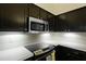 Detailed view of the kitchen featuring dark wood cabinets, stainless steel appliances, and sleek white countertops at 3438 Farmers Market Dr, Charleston, SC 29414