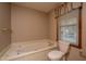 Relaxing bathroom with a soaking tub, toilet, and window with natural light at 406 Mendenhall St, Summerville, SC 29483