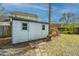 A white shed in a backyard setting, with flower bushes and sparse vegetation at 406 Mendenhall St, Summerville, SC 29483