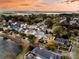 Aerial view shows neighborhood street lined with houses and a small lake in the background at sunset at 4108 Whiting St, Mount Pleasant, SC 29466