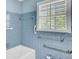 Classic bathroom with blue tile walls, window, and safety bars near the white bathtub at 649 Pawley Rd, Mount Pleasant, SC 29464