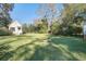 Spacious backyard featuring lush green grass, mature trees, and a charming cottage at 8115 Adams Run School Rd, Adams Run, SC 29426