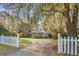 Charming two-story home with white picket fence, lush landscaping, and grand trees draped in Spanish moss at 8115 Adams Run School Rd, Adams Run, SC 29426