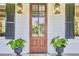 Close up of a warm wood front door flanked by stylish sconces and elegant potted plants at 8115 Adams Run School Rd, Adams Run, SC 29426