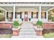 Close up of front porch with elegant white columns, brick accents, plants, and striking wood door at 8115 Adams Run School Rd, Adams Run, SC 29426