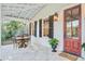 Cozy porch featuring an outdoor dining set, natural stone flooring, and a stylish wood door at 8115 Adams Run School Rd, Adams Run, SC 29426