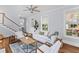 Well-lit living room with hardwood floors, staircase and comfortable seating around a center table at 1100 Sea Island Crossing Ln, Mount Pleasant, SC 29464