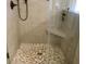 Close-up of a modern shower with pebble flooring, tiled walls, and glass doors at 112 Carpenter St, Summerville, SC 29486