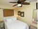 Comfortable bedroom with a ceiling fan, palm tree art, and ample natural light at 1300 Ocean Blvd # 139, Isle of Palms, SC 29451