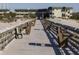Long wooden pier with benches along the sides leading to condo buildings in the distance at 1300 Ocean Blvd # 139, Isle of Palms, SC 29451