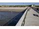 Long wooden pier view with people fishing on a sunny day in front of buildings in the distance at 1300 Ocean Blvd # 139, Isle of Palms, SC 29451