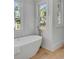 Bright bathroom with a freestanding tub placed near windows offering views of palm trees, enhancing a spa-like atmosphere at 178 Beresford Creek St, Daniel Island, SC 29492