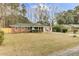 Charming one-story home with a red brick and white exterior, complemented by a large well-manicured lawn and mature trees at 211 Logan Dr, Summerville, SC 29483