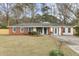 Charming one-story home with a red brick and white exterior, complemented by a well-manicured lawn and mature trees at 211 Logan Dr, Summerville, SC 29483