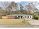 Charming one-story home with a red brick and white exterior, complemented by a well-manicured lawn and mature trees at 211 Logan Dr, Summerville, SC 29483