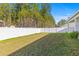 Spacious backyard featuring a lush lawn and a white vinyl fence, creating a private outdoor space at 223 Sugarberry Lane, Moncks Corner, SC 29461