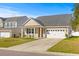 Single-story home featuring tan siding, black shutters, well-manicured lawn, and an attached white single-car garage at 223 Sugarberry Lane, Moncks Corner, SC 29461