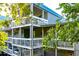 Multi-level condo building with white wood railings and a blue metal roof, surrounded by mature trees at 2472 Racquet Club Dr, Seabrook Island, SC 29455